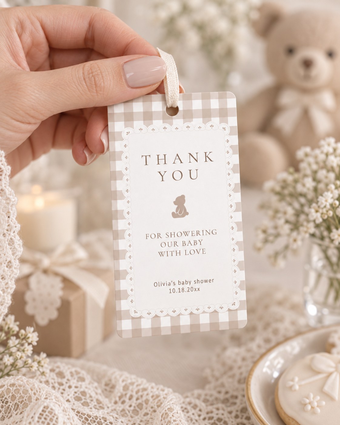 Hand holding a printed teddy bear gingham baby shower favor tag with a white lace frame